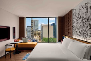 A hotel room with a large bed, a small table with a chair, a sofa, a TV, and a large window with a city view. - Hotel Indigo Saigon The City by IHG (Ho Chi Minh City)