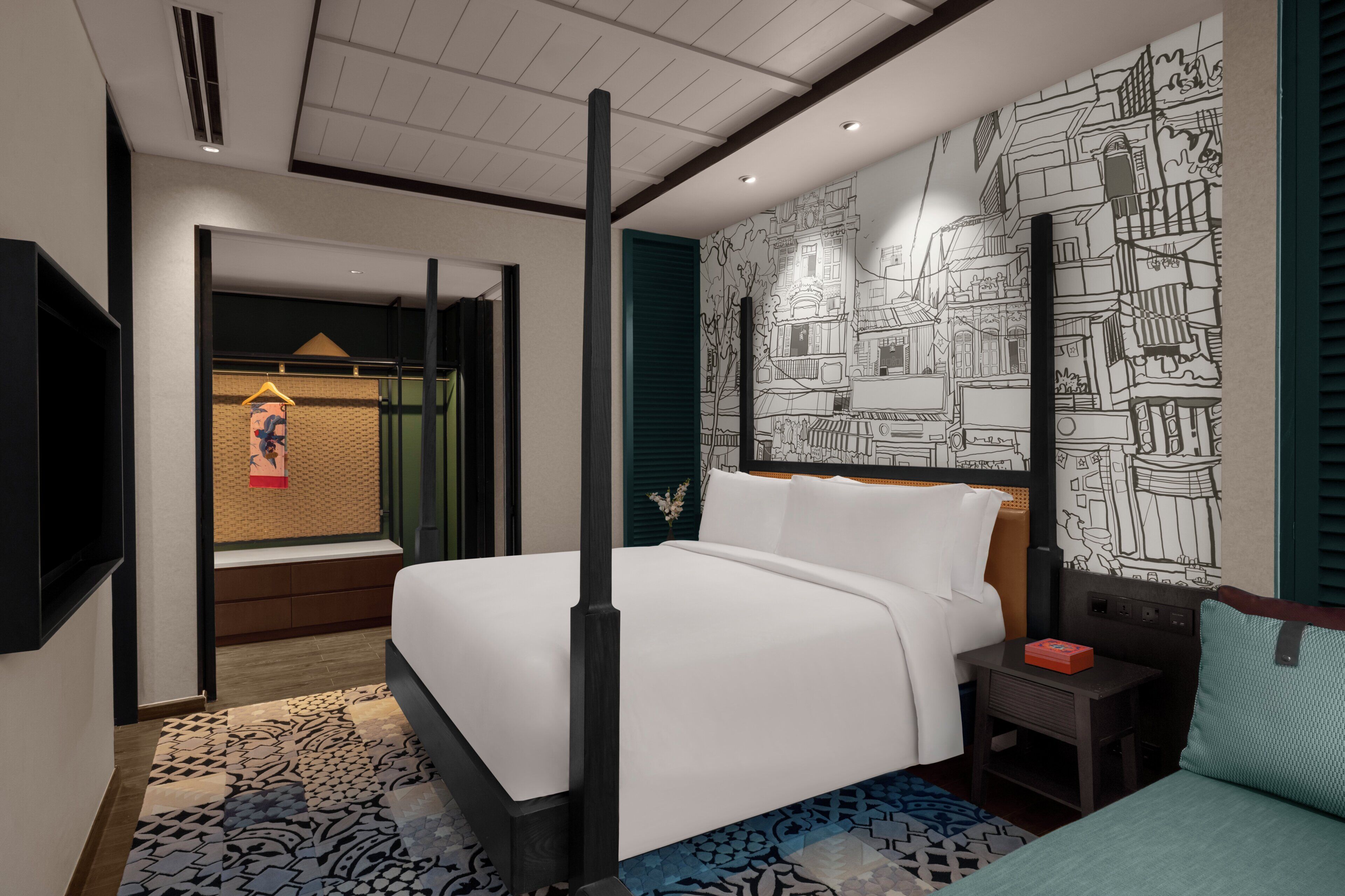 A hotel room with a four-poster bed, a small bedside table, a nightstand, and a wall with a cityscape mural.