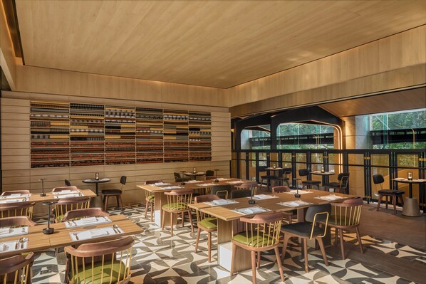 Un restaurante moderno con mesas y sillas de madera, un suelo con diseño y una amplia estantería en la pared.