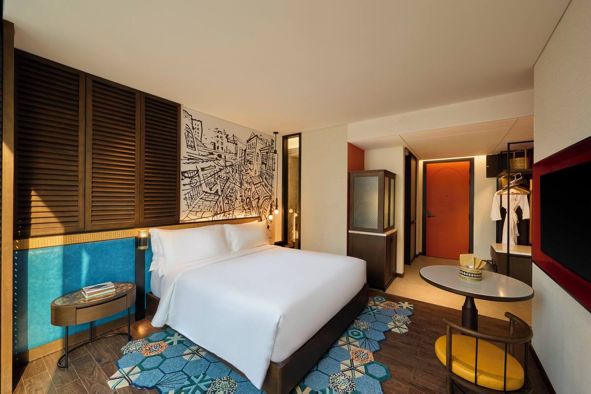 Une chambre d’hôtel avec un lit, une petite table, une chaise, un téléviseur et une armoire.