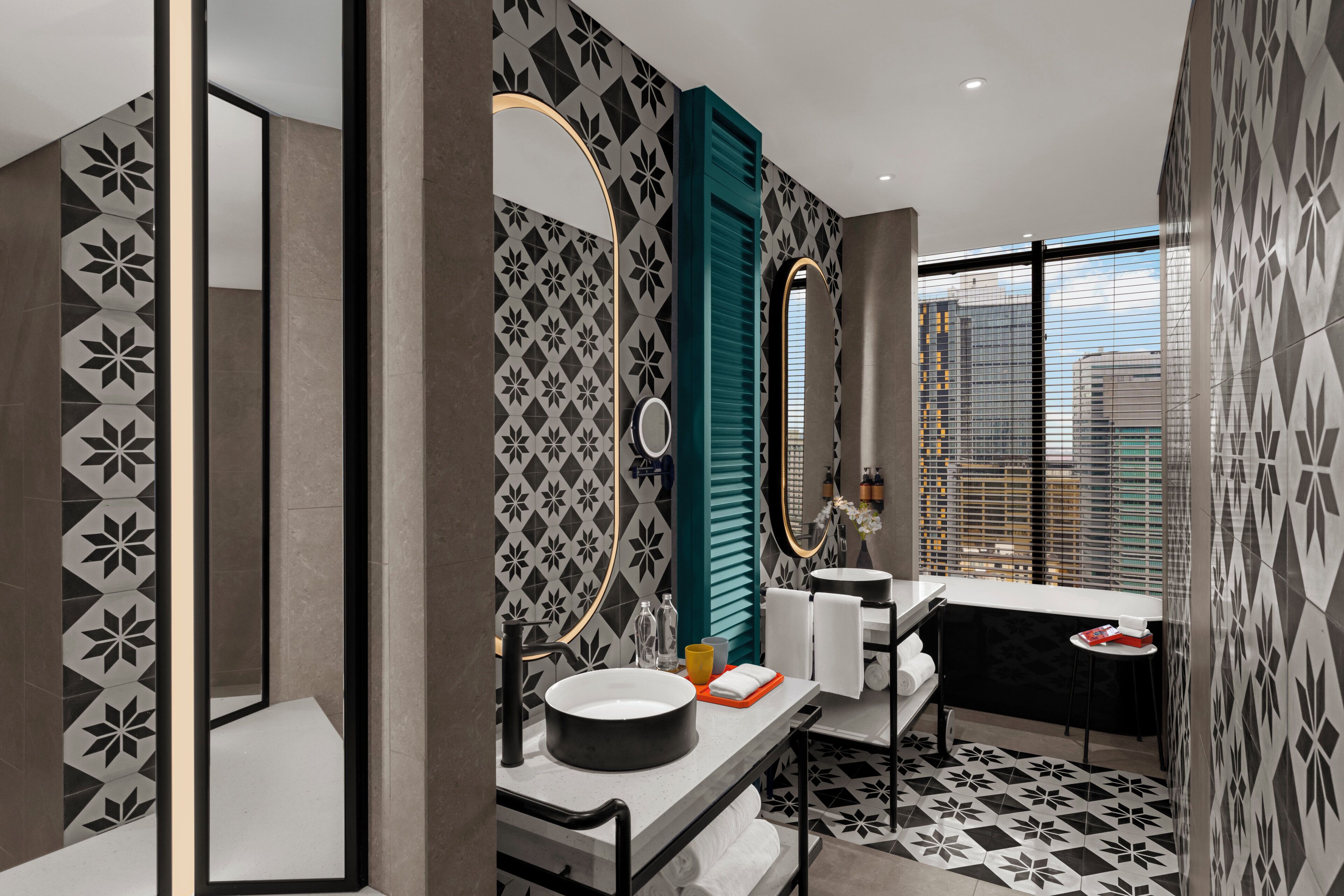 Une salle de bain moderne avec un grand miroir, un lavabo rond et une fenêtre avec des stores.