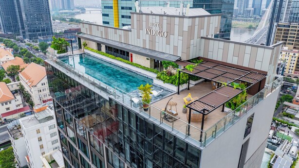 A hotel with a rooftop pool, outdoor seating, and a view of the cityscape. - Hotel Indigo Saigon The City by IHG (Ho Chi Minh City)