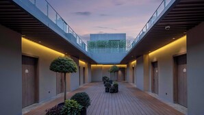 A modern hotel corridor with wooden flooring, potted plants, and a glass railing overlooking a green area. - Holiday Inn Express Shanghai Hongqiao NECC by IHG (Shanghai)