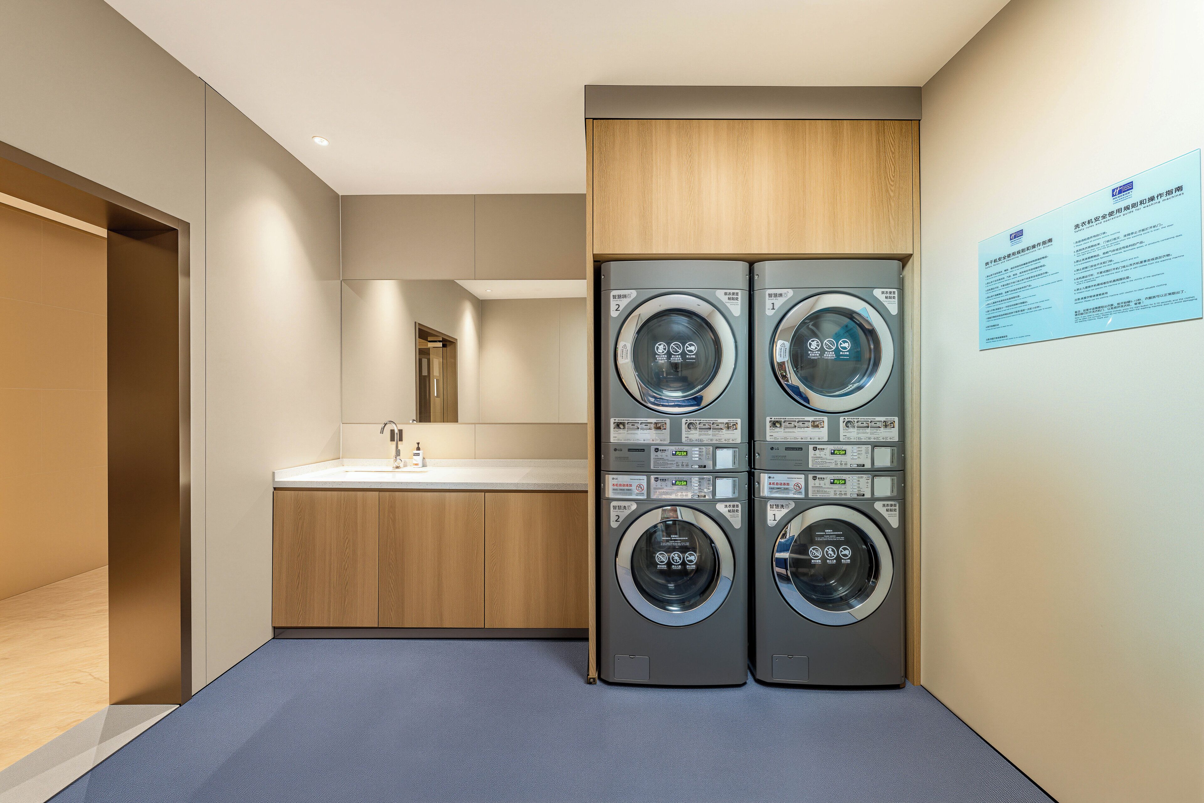 Habitación de hotel con lavadora y secadora integradas, un lavamanos y un espejo.