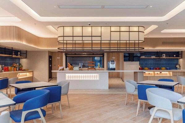 Un restaurante moderno con una barra central, sillas azules y blancas, y piso de baldosas.