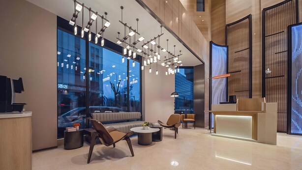A modern hotel lobby with a reception desk, seating area, and large windows offering city views. - Holiday Inn Express Shanghai Hongqiao NECC by IHG (Shanghai)