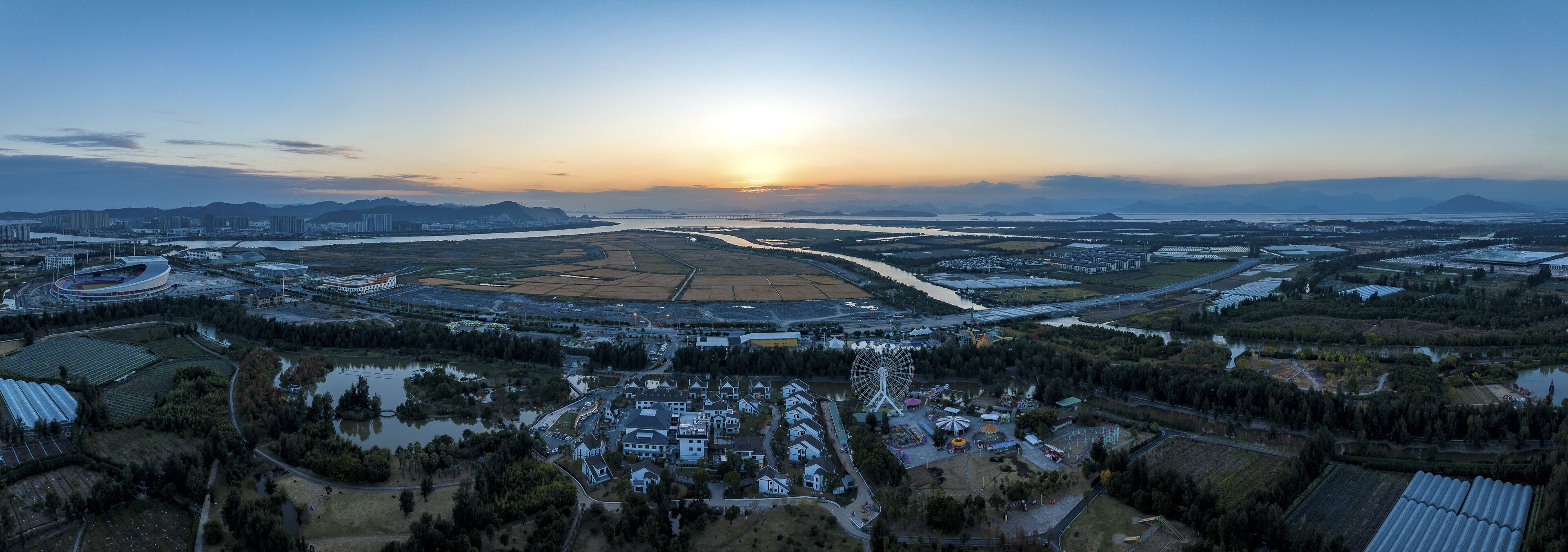 Vue aérienne d’un quartier résidentiel avec des maisons, une grande grande roue et une rivière.