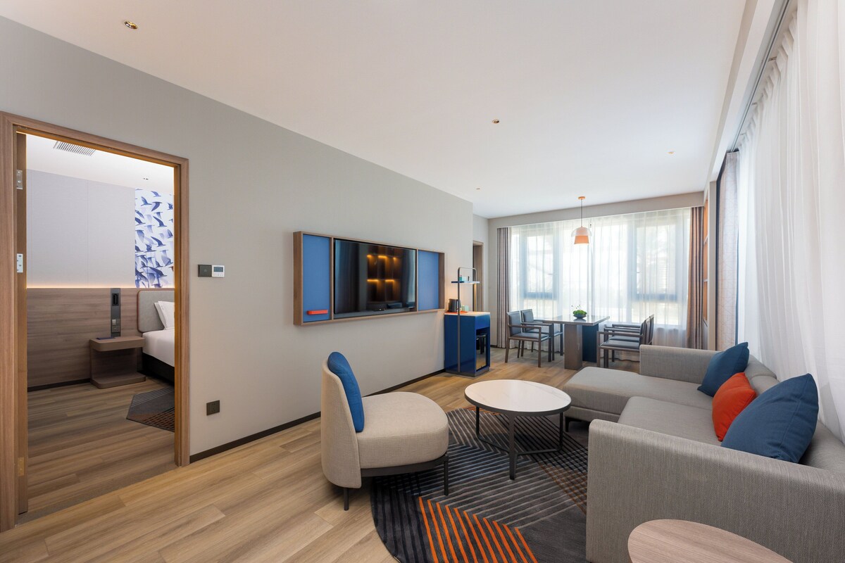 Une chambre d’hôtel moderne équipée d’un canapé, d’un fauteuil et d’un coin repas avec une table et des chaises.