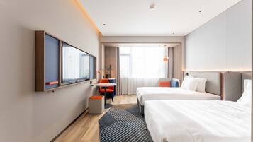 A hotel room with two beds, a desk, a chair, a TV, and a window with curtains.
