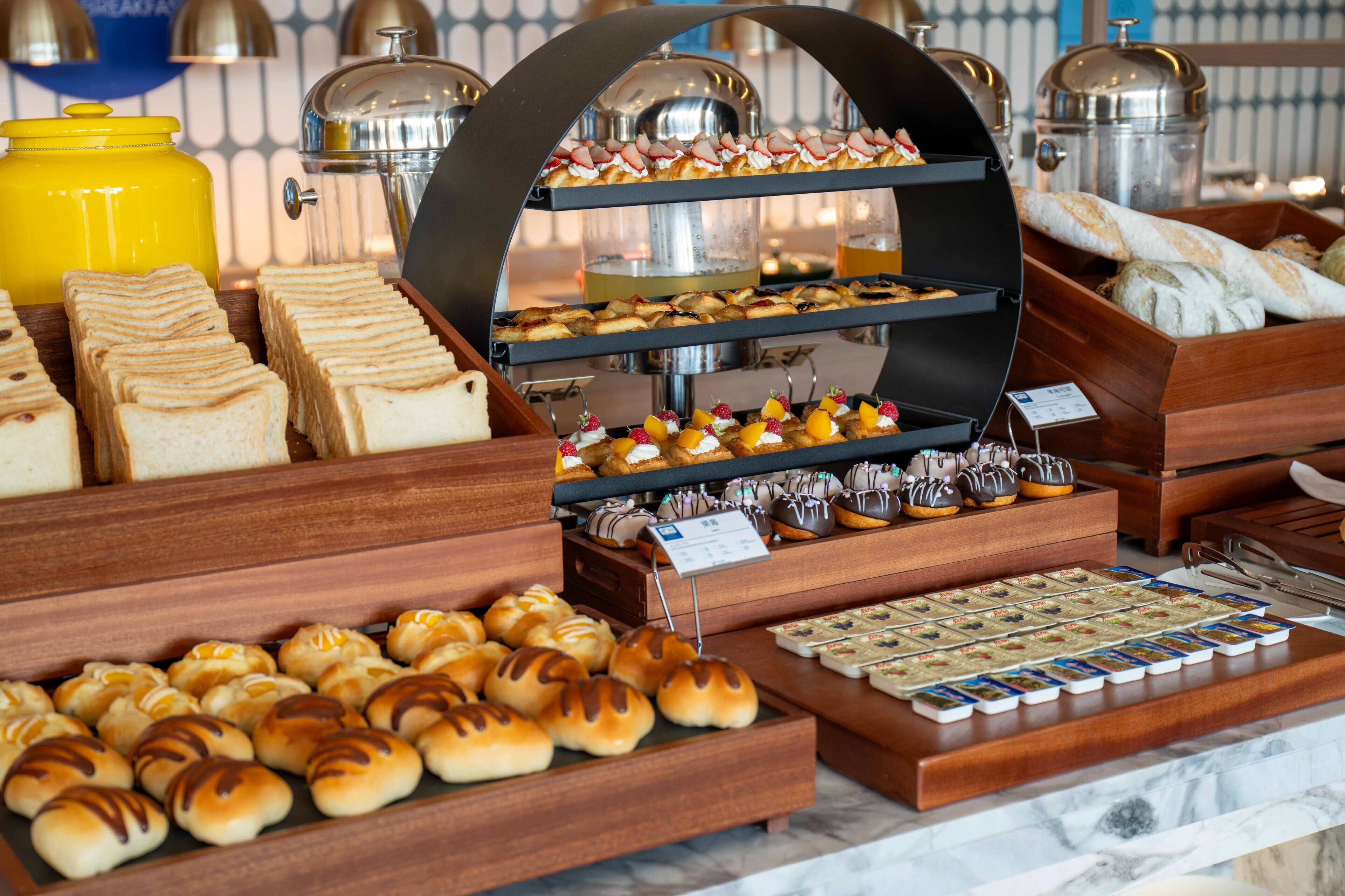 A buffet with various food items including bread, pastries, and desserts.