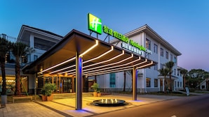 L’entrée d’un hôtel, avec un passage couvert, des palmiers et une enseigne indiquant « Holiday Inn Express ».