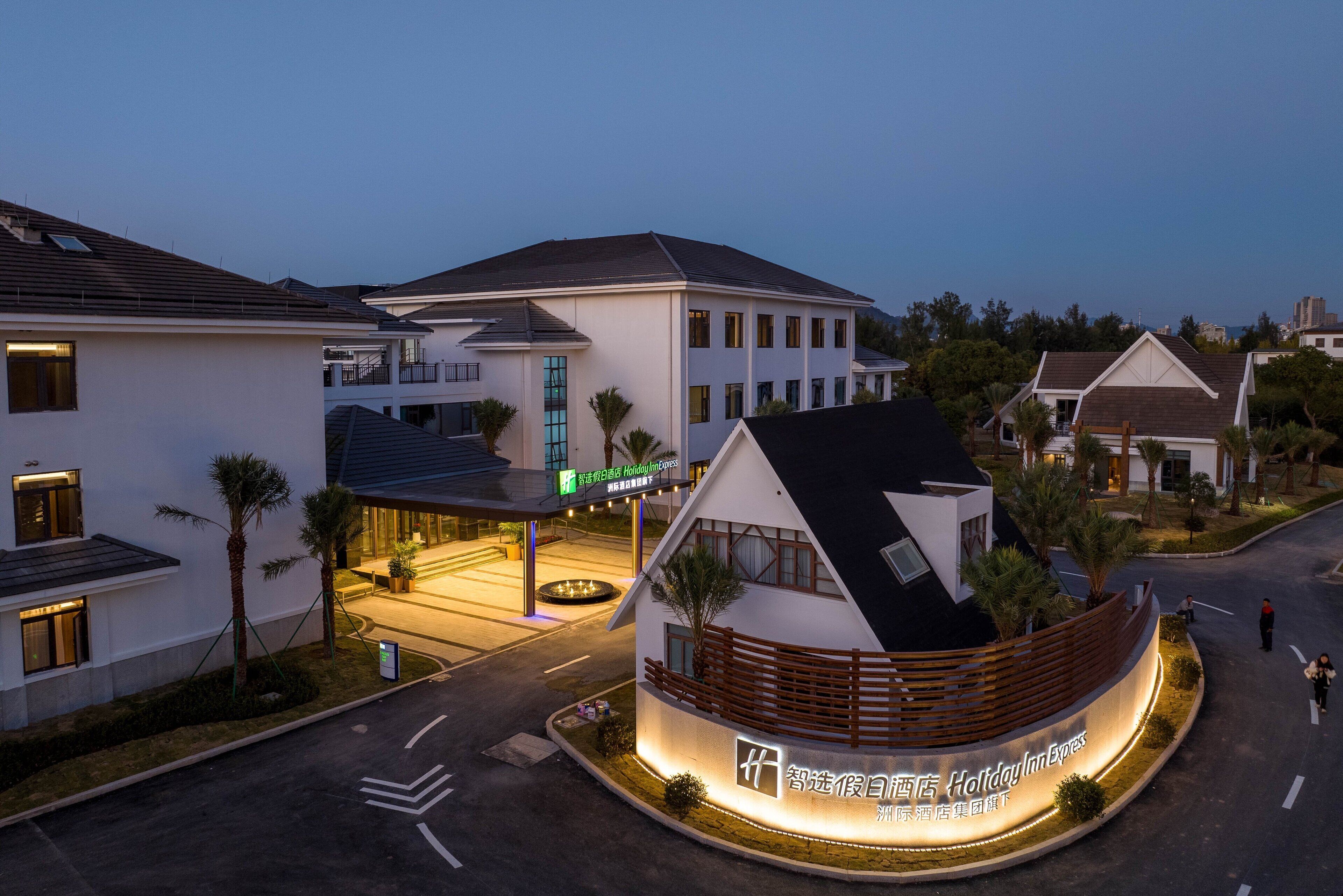 A Holiday Inn Express hotel with a modern design, featuring a curved facade and a well-lit entrance.