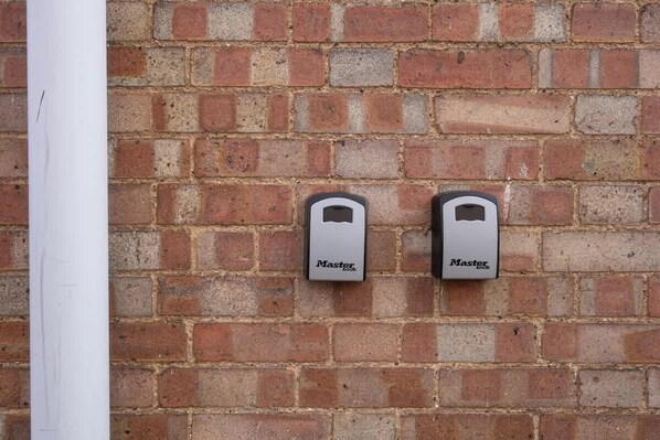 Two Master Lock padlocks mounted on a brick wall.
