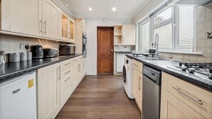A kitchen with wooden cabinets, a dishwasher, and a stove. - 3 Bedroom Home With 2 Bathrooms & Free Parking (Bedford)