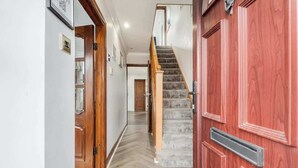 A hallway with a wooden door, a staircase with a handrail, and a herringbone-patterned floor. - 3 Bedroom Home With 2 Bathrooms & Free Parking (Bedford)