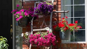 A brick building with a wooden ladder supporting hanging flower baskets. - Ravine House, 4000sqf, View, AC,Sleep12+

 (Calgary)