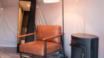 Una silla con respaldo alto y apoyabrazos, ubicada junto a un altavoz negro y una lámpara de pie.