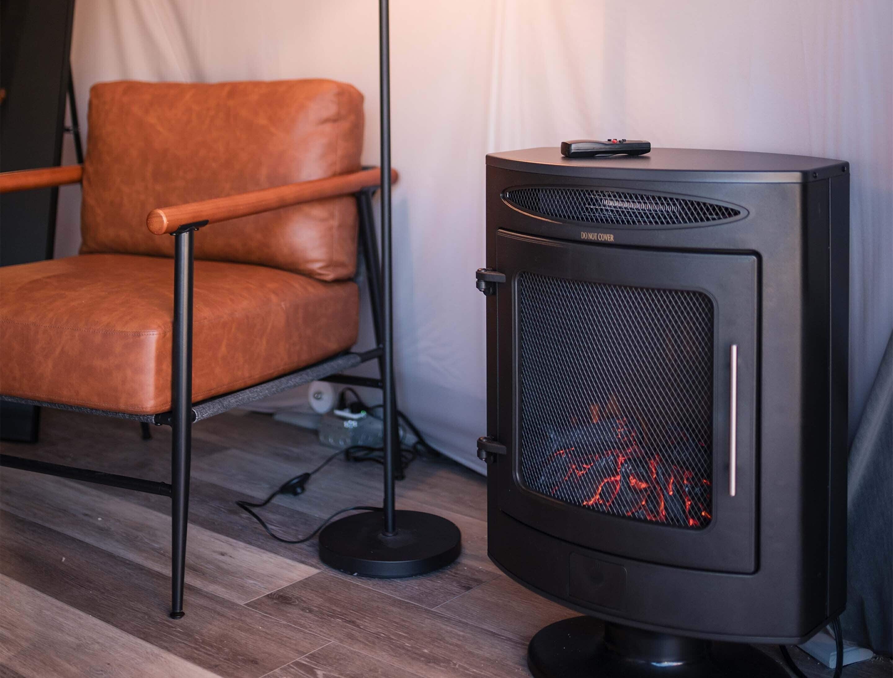 Quarto com uma poltrona de couro, um aquecedor preto com grade frontal e um cabo elétrico no chão.