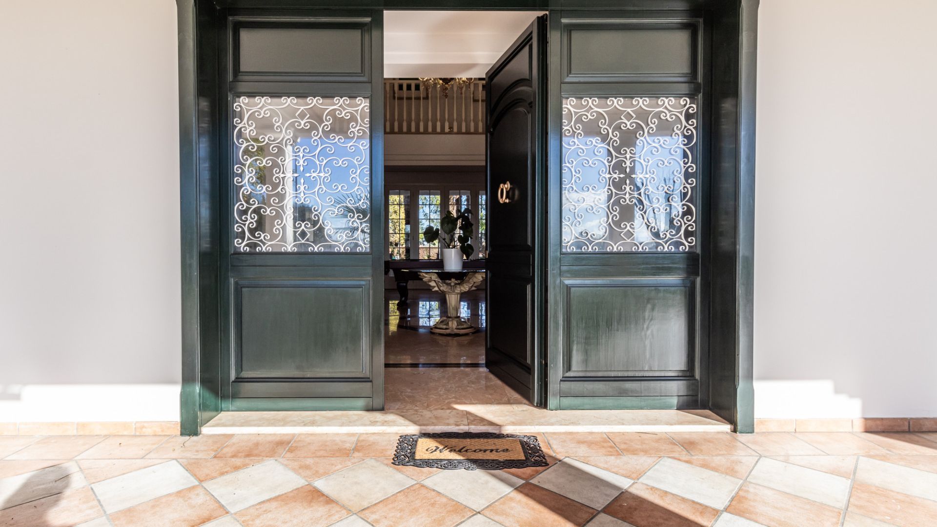 L’entrée d’un hôtel, avec une porte en bois sombre, un paillasson et un sol carrelé.