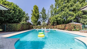 Una piscina con agua azul cristalina, rodeada de abundante vegetación y árboles.