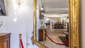 A grand hallway with a large ornate mirror, a red rope barrier, and a staircase leading to a dining area. - Villa Petrone | Luxury Home-Wi-Fi,Biliardo,Jacuzzi (Emilia-Romagna)