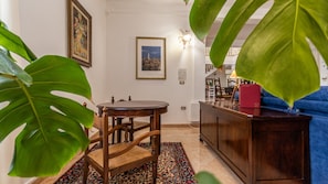 A room with a round wooden table, a blue sofa, a patterned rug, and a framed picture on the wall.