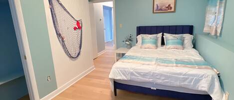 A bedroom with a bed, a door with a net, and a hallway leading to another room.