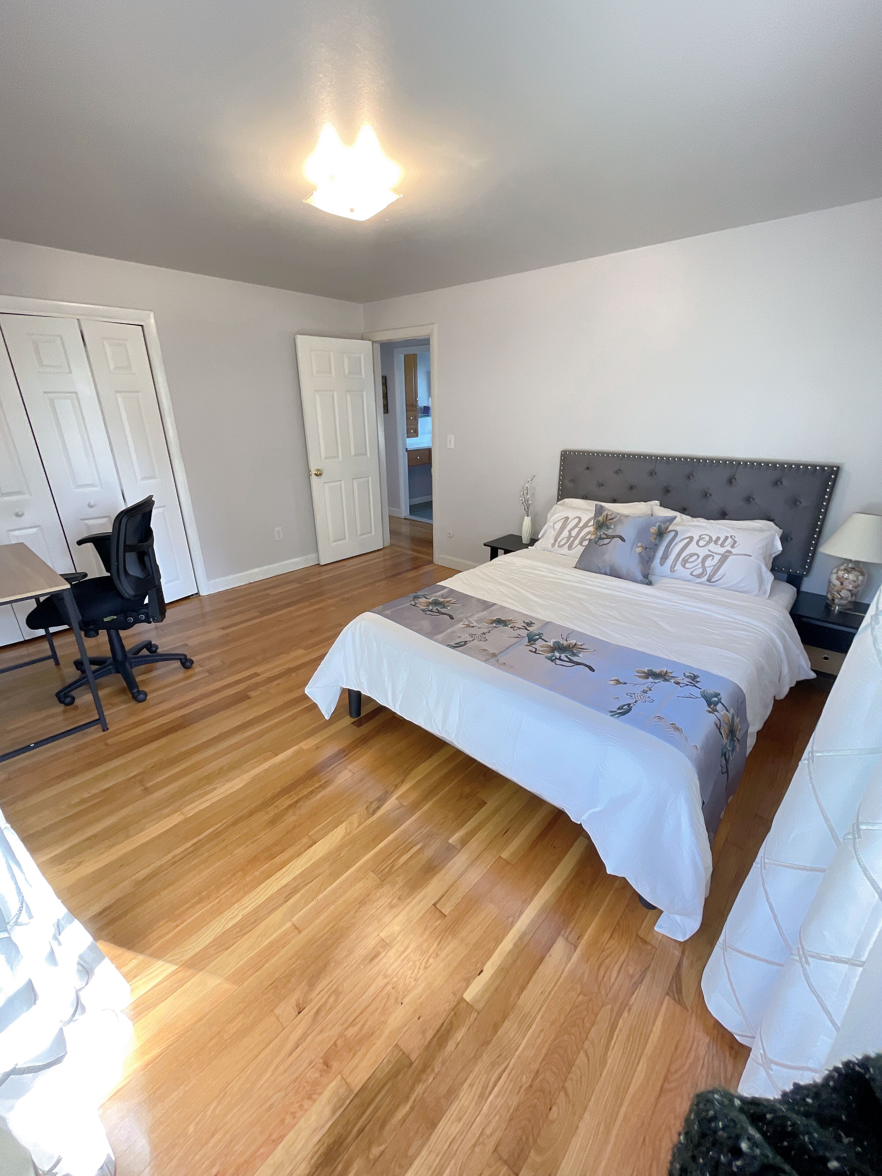 A bedroom with a bed, a desk, and a chair.