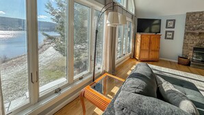 A spacious living room with large windows, a stone fireplace, and a cozy seating area.