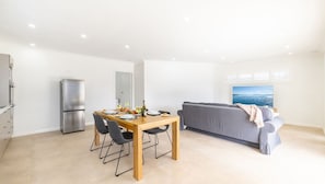 Un espacio habitable moderno con zona de comedor, un sofá gris y un ventanal con vistas.