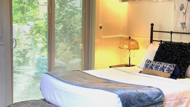 Une chambre à coucher avec un lit, une table de chevet, une lampe et une fenêtre avec des stores.