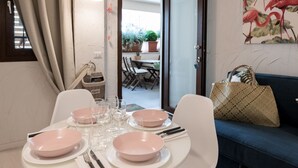Un coin repas avec une table dressée pour quatre personnes, des chaises et un canapé bleu agrémenté d’un sac en tissu tressé.