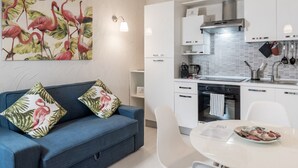 Une cuisine moderne avec des armoires blanches, une hotte en acier inoxydable et un coin repas comprenant une table et des chaises blanches.