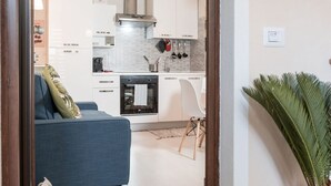 Une cuisine moderne avec des armoires blanches, une hotte de cuisinière en acier inoxydable et un four encastré.
