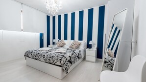 Une chambre moderne avec un grand lit, une table de chevet, une chaise et un mur à rayures.