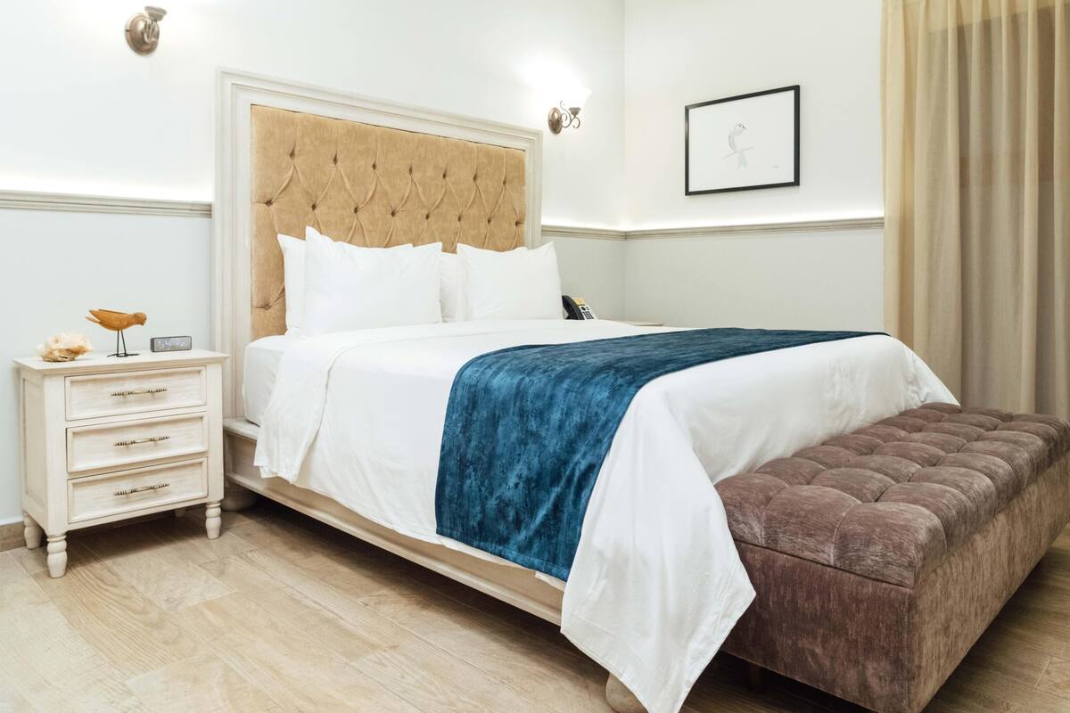 A neatly arranged hotel room with a bed, bedside table, and a small table with items on it.