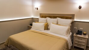 A hotel room with a bed, bedside tables, a nightstand, and a wall-mounted phone. - Voco Royalty Puebla Downtown (Puebla)
