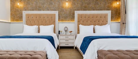 A hotel room with two beds, a nightstand, a wooden floor, and a patterned wallpaper.