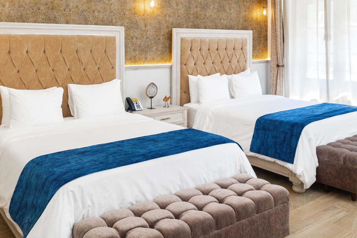 Un lit double agrémenté d’une touche de bleu, une table de chevet avec une lampe et un téléphone fixé au mur.