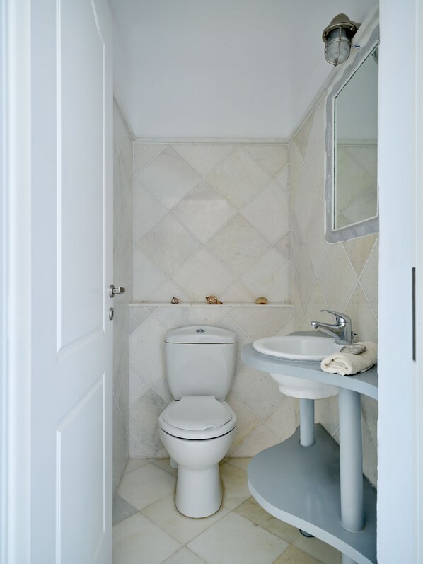 A small, modern bathroom with a toilet, sink, and mirror. - Cycladic Villa, Blue Stories. (Naousa)
