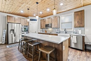 Una cocina moderna con armarios de madera, electrodomésticos de acero inoxidable y una isla grande con taburetes de bar.