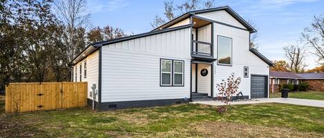 A two-story house with a front porch, a small garden, and a wooden fence.
