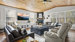 A living room with a fireplace, leather sofas, a large TV, and wooden flooring.