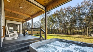 A hot tub on a wooden deck with a view of trees.