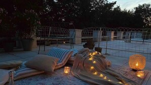 An outdoor seating area with lounge chairs, blankets, and candles. - Royal Rose (Étretat)