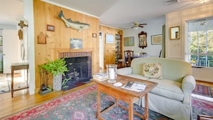 A cozy living room with a fireplace, wooden walls, a green sofa, and a patterned rug.