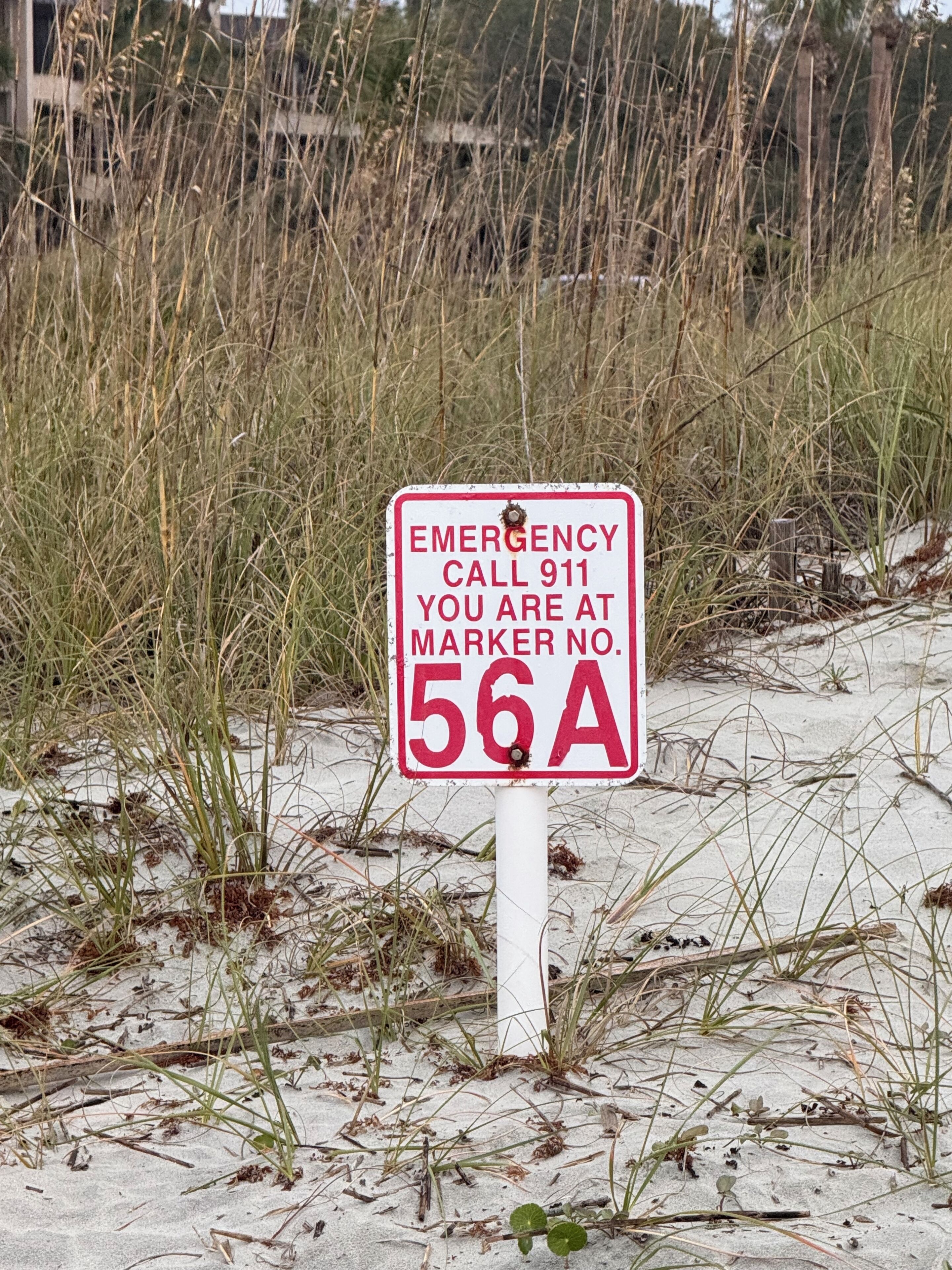 Ein Warnschild am Strand mit einer Vermessungsnummer.