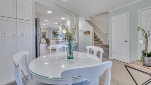 A modern kitchen with white cabinetry, a round glass table, and white chairs. - Pet-Friendly Coligny Villa- Minutes to Beach & Celebration Park! (Hilton Head Island)