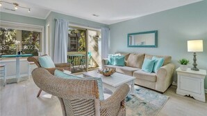 A living room with wicker furniture, a white sofa with blue cushions, a coffee table, and a side table with a lamp. - Pet-Friendly Coligny Villa- Minutes to Beach & Celebration Park! (Hilton Head Island)