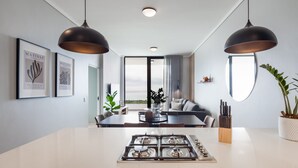 Un espace de salle à manger moderne avec un îlot central, des luminaires suspendus et des œuvres d’art accrochées aux murs.